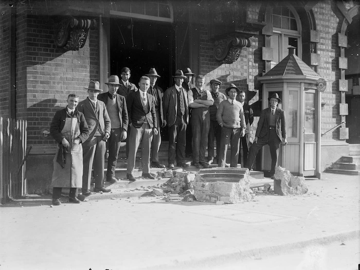 Men standing behind some fallen masonry after the Murchison earthquake