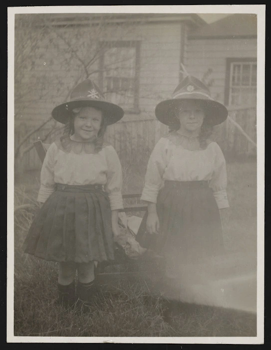 Two young girls wearing World War I servicemen's hats