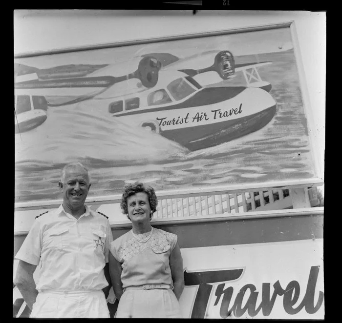 Fred and Mabel Ladd with Tourist Air Travel sign, Auckland Airport