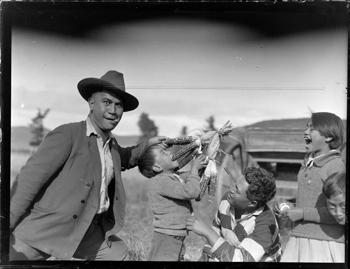 Māori children and a Māori man having fun with coloured maize, Taupō
