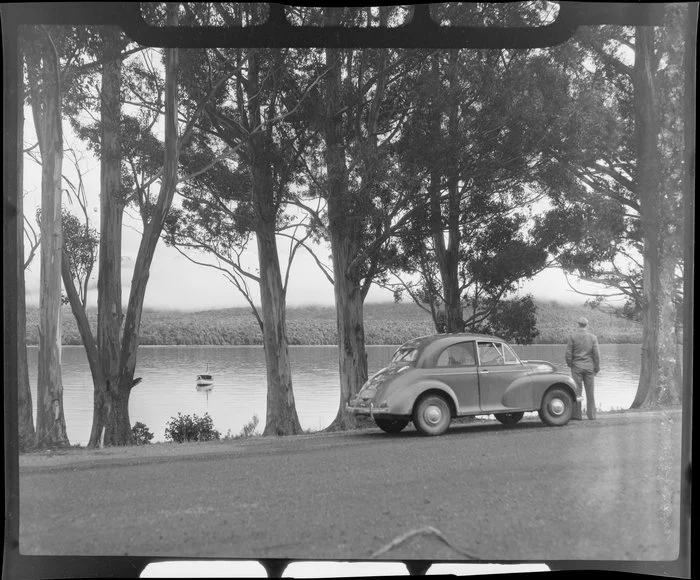 Unidentified man and Morris Minor beside Lake Te Anau, Southland district