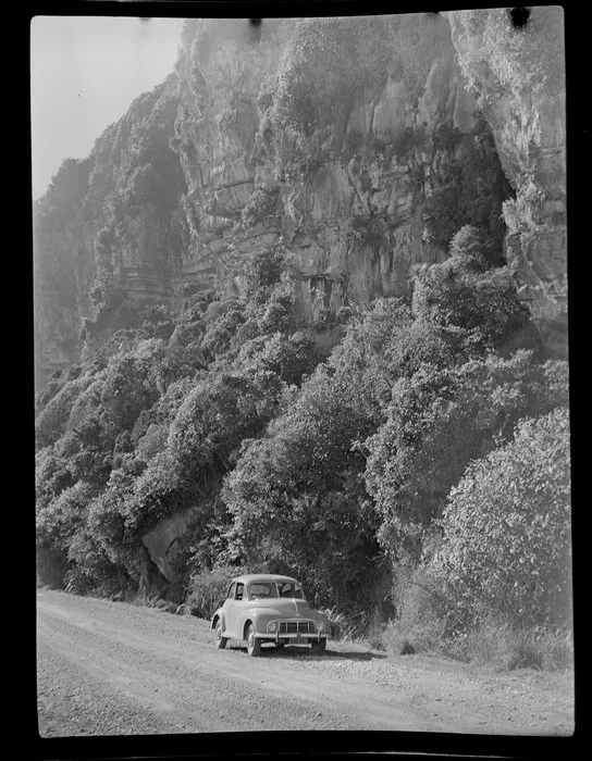 Morris Minor parked under cliff on the road near Punakaiki, Buller district