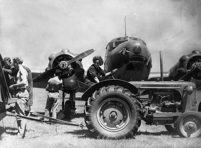 Woman driving a tractor alongside a Avro Anson training plane, during World War II