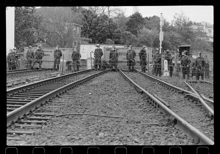 Line of police behind fencing on a railway line