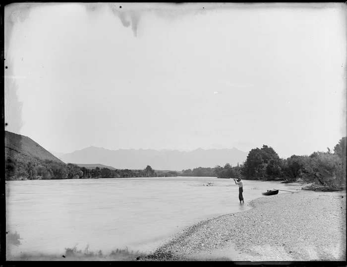 Unidentified man firing a gun while standing in the shallows of the Clinton River, Southland Region