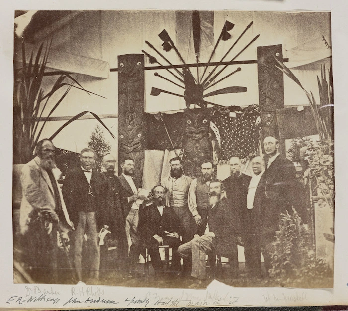 Group including Dr A C Barker, R H Rhodes and W M Maskell, alongside a display of Maori artifacts