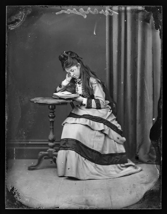 Young woman [from Wargan family] looking at photograph album