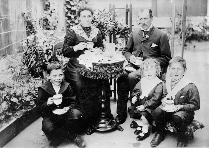 Man, woman and three children, having afternoon tea
