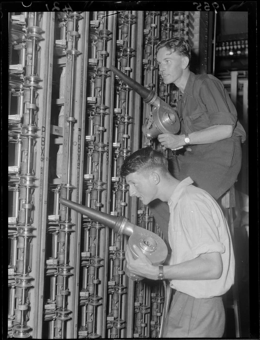 Two unidentified men dry out the telephone switches using electric blowers