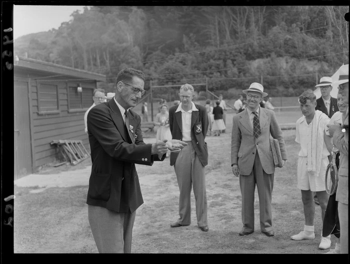 Mr V Salek demonstrating the use of a dowsing rod to a group, at a national tennis tournament, location unidentified