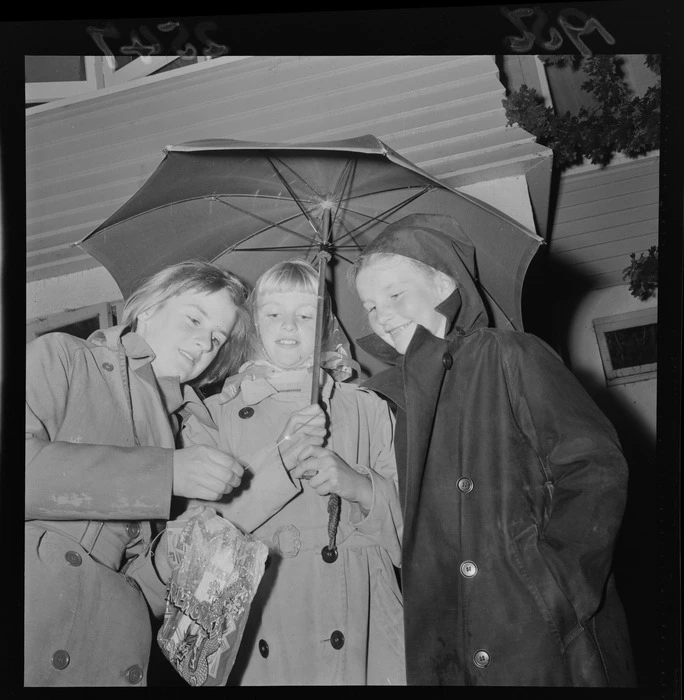 Three unidentified Hutt Valley girls under an umbrella on Guy Fawkes, including a sparkler and bag of fireworks