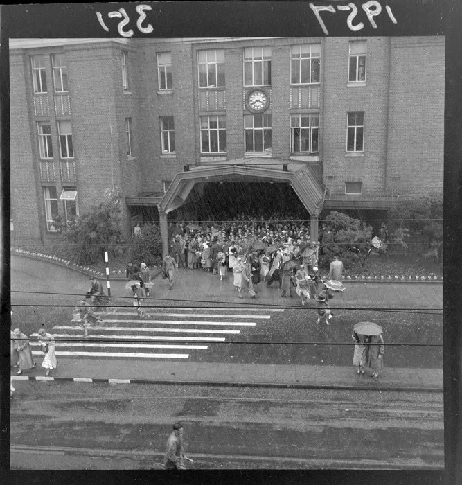 Train commuters sheltering from the rain, under an entranceway on the west side of the Wellington Railway Station, during a flood