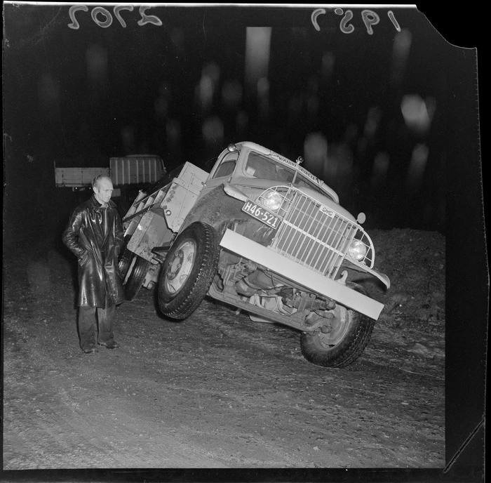 Truck stuck in mud on Wainuiomata Hill and an unidentified man next to the truck, Lower Hutt