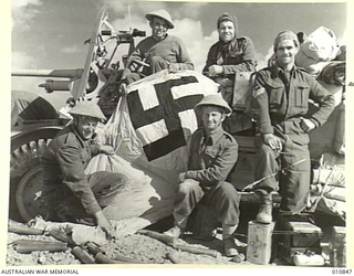 WESTERN DESERT.  NEW ZEALAND GUN CREW WITH THE NAZI FLAG THAT WAS WRAPPED AROUND THE TURRET OF THE TANK THEY CAPTURED, WHICH WAS A BRITISH MATILDA TANK THAT THE GERMANS HAD CAPTURED AND USED.  THE ..