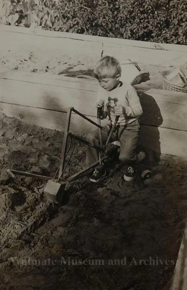 Boy playing with toy digger in sandpit