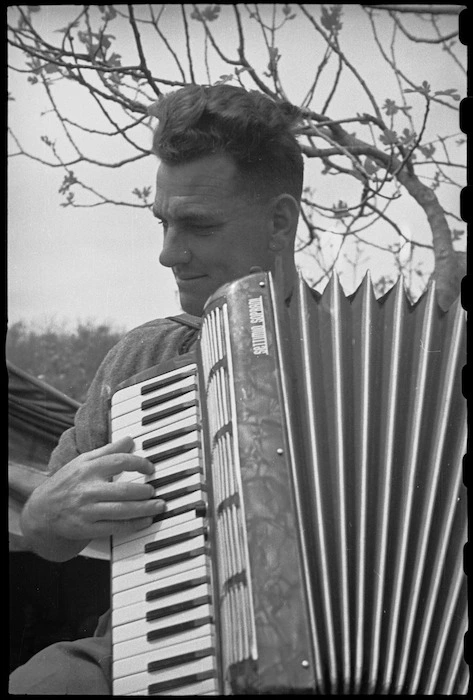 G Hyde of 6 NZ Infantry Brigade Band plays a piano accordian when off duty, Italy, World War II - Photograph taken by George Bull
