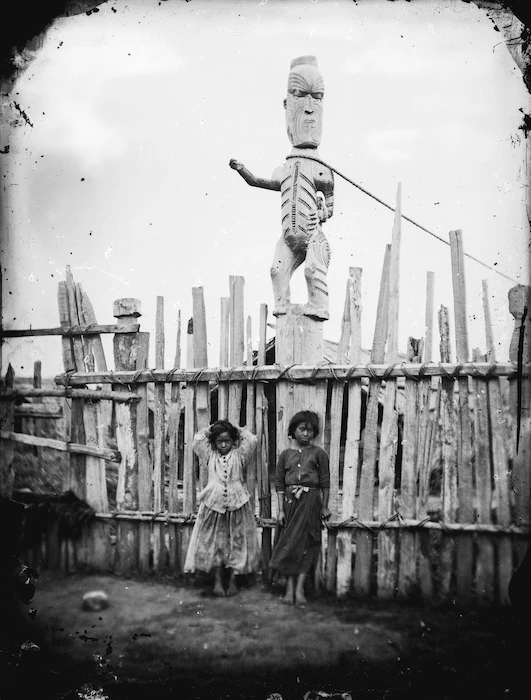 Maori children and carved figure on a post, at a pa in Wanganui